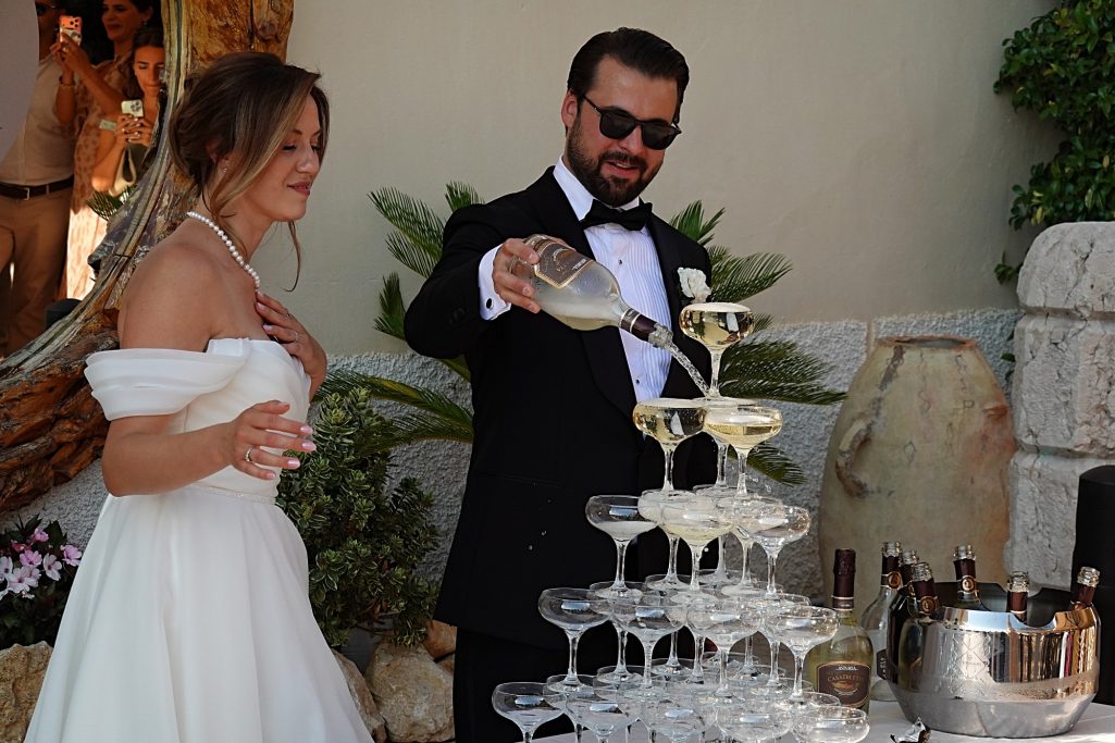 Brautpaar bei einer Hochzeit, der Bräutigam gießt Champagner in ein Glasturm.