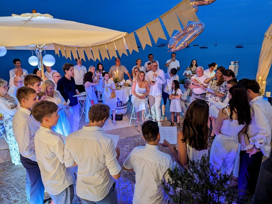 Festliche Versammlung bei Nacht, Menschen in weißer Kleidung, Feierlichkeiten im Freien.